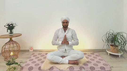 Einblick in den Yogaraum mit Kundalini Yogalehrer Fabian sitzend in Gebetshaltung